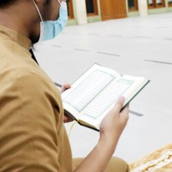 person in brown shirt holding white book