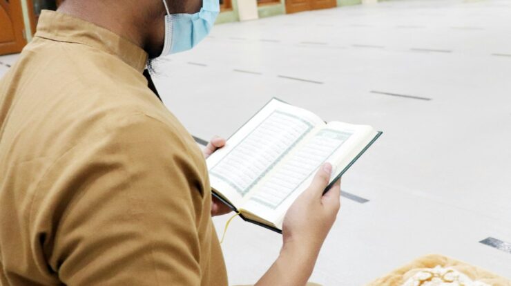 person in brown shirt holding white book