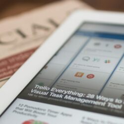 white tablet computer on top of newspaper