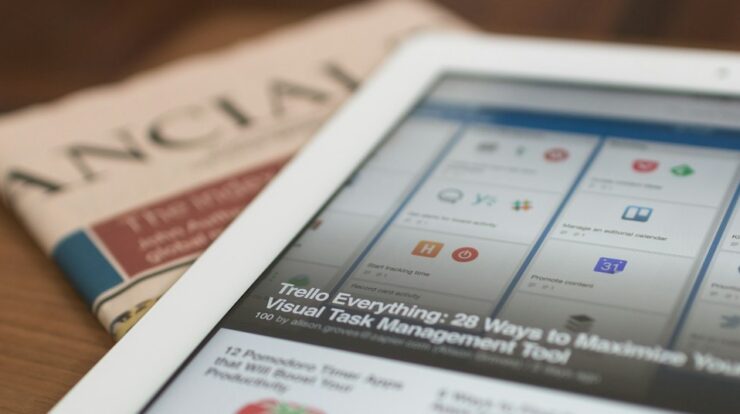 white tablet computer on top of newspaper
