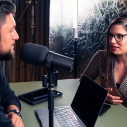 a man and a woman wearing headphones and looking at a laptop