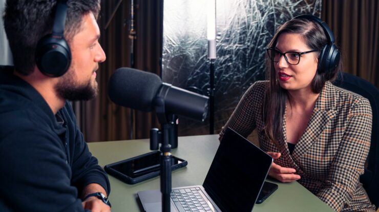 a man and a woman wearing headphones and looking at a laptop