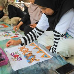 Women painting batik designs on fabric