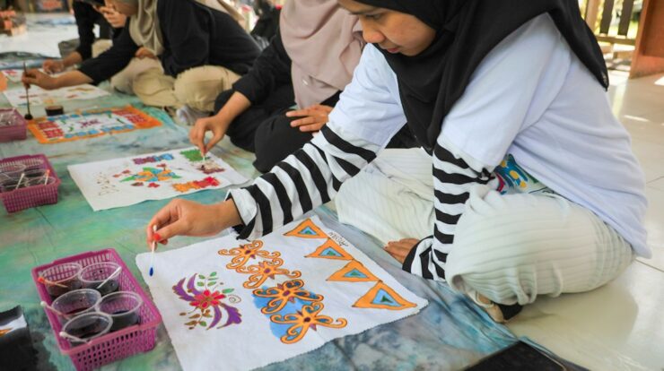 Women painting batik designs on fabric