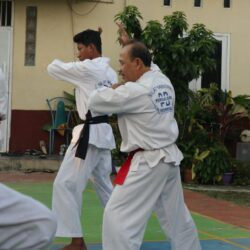 A group of men practicing karate in front of a building