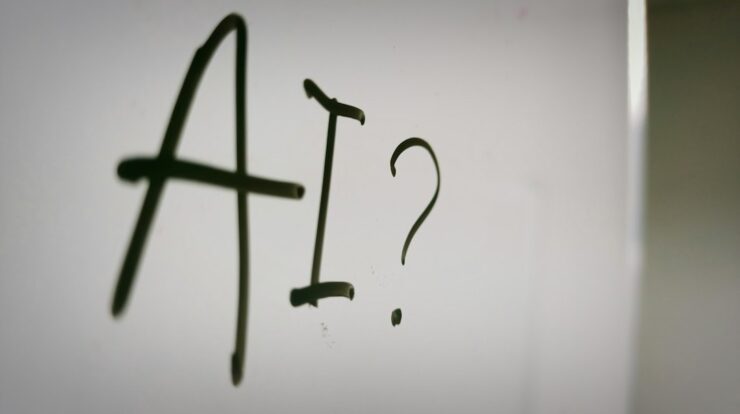 The letters AI and a question mark written in black marker on a whiteboard