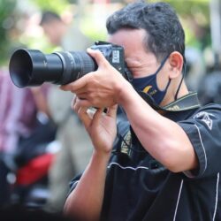 man in black and yellow polo shirt holding black dslr camera