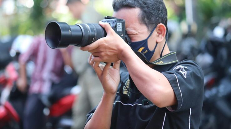 man in black and yellow polo shirt holding black dslr camera