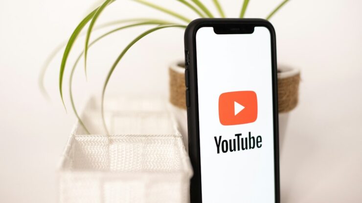 a phone with a youtube logo on it next to a potted plant