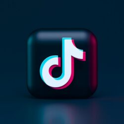 A three-dimensional TikTok logo with cyan and magenta chromatic aberration on a dark background