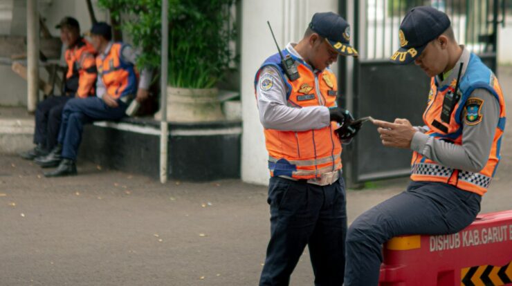 Two traffic officers in orange vests check their phones