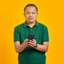 a man in a green shirt looking at a cell phone