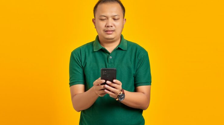 a man in a green shirt looking at a cell phone