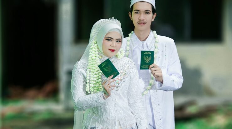 Newlyweds holding marriage books in traditional attire