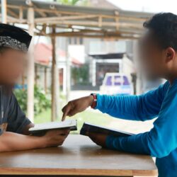 two boys sitting at a table with a book