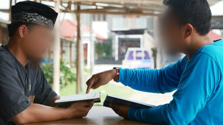 two boys sitting at a table with a book