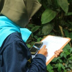 a person in a hijab writing on a clipboard