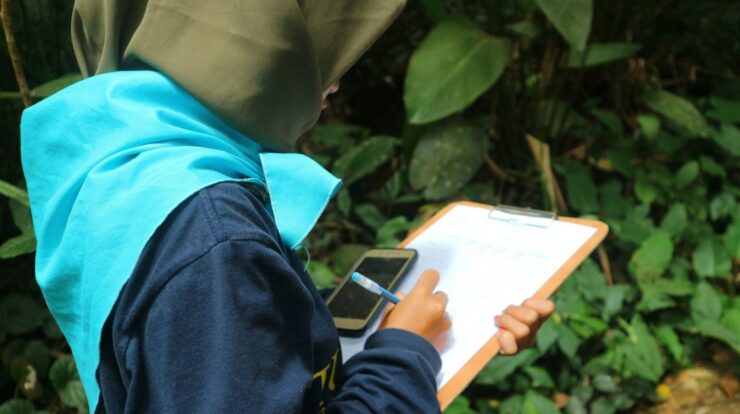 a person in a hijab writing on a clipboard