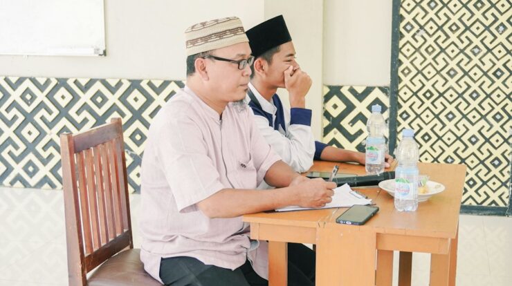 Two men wearing kufi caps attend a meeting