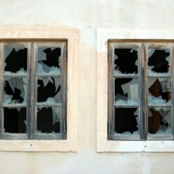 two broken 6-pane windows on white painted wall