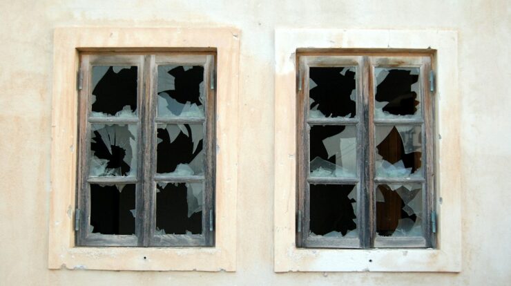 two broken 6-pane windows on white painted wall