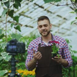 Man holding a potted plant in a greenhouse
