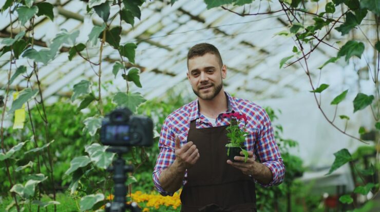 Man holding a potted plant in a greenhouse