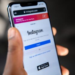 A hand holding a smartphone displaying the Instagram login page on a screen