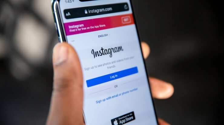 A hand holding a smartphone displaying the Instagram login page on a screen