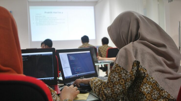 woman wearing grey hijab using laptop compiter